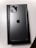 A sleek smartphone with a metallic finish is placed on top of its box. The back showcases three camera lenses and the iconic logo in the center, highlighting its premium design.