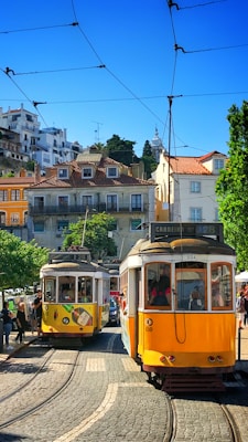 people inside yellow tram and others are standing near road during daytime