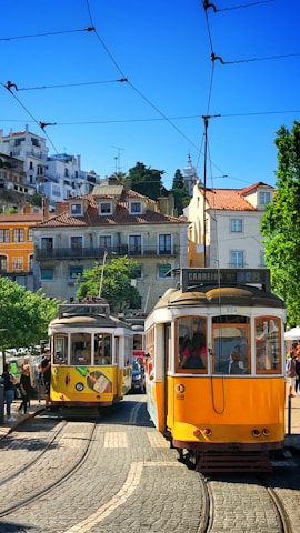 people inside yellow tram and others are standing near road during daytime