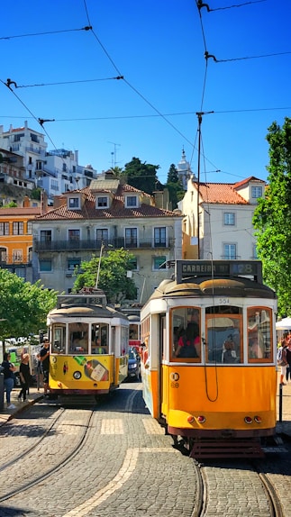 people inside yellow tram and others are standing near road during daytime