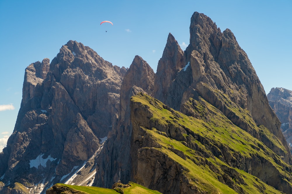 person paragliding above mountain under blue and white sky during daytime