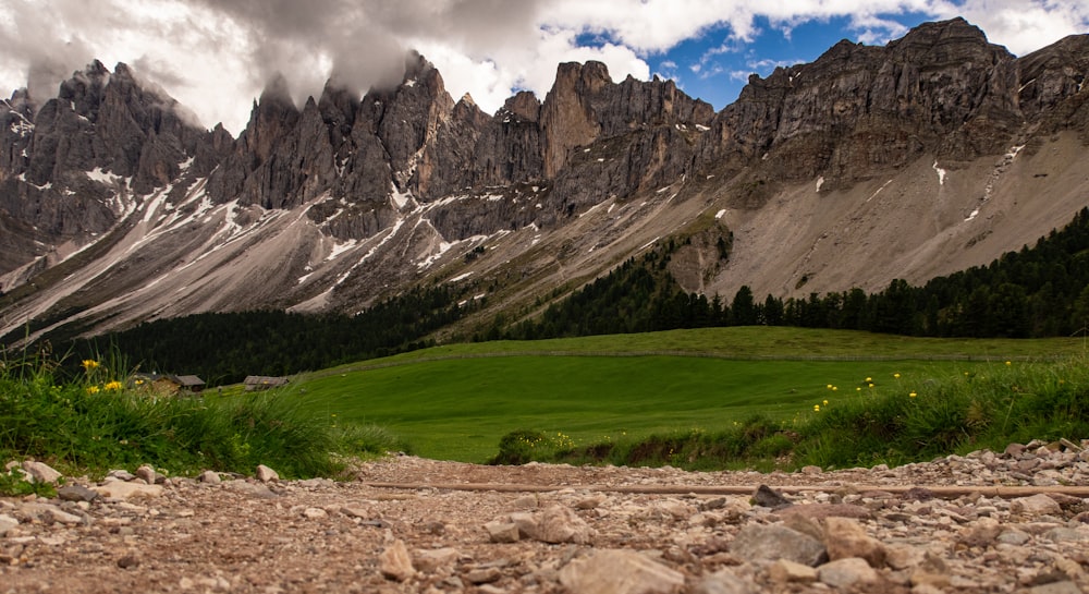 green field viewing mountain under white and blue sky during daytime