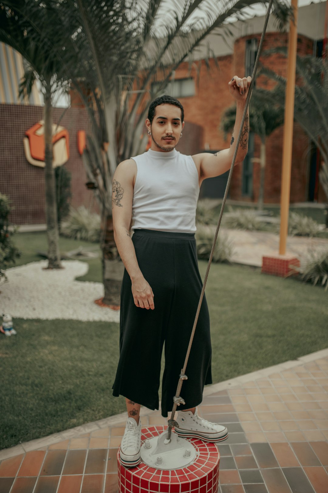 man wearing grey sleeveless shirt and black pants standing on platform with cable