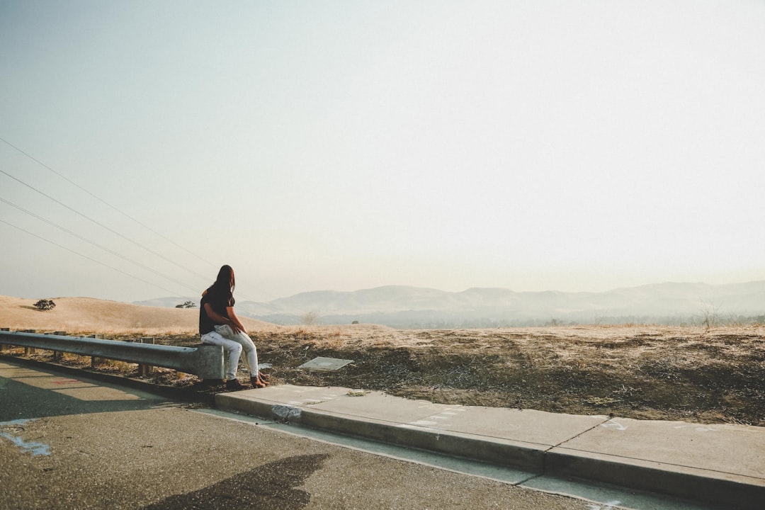 woman sitting on gray barrier during daytime