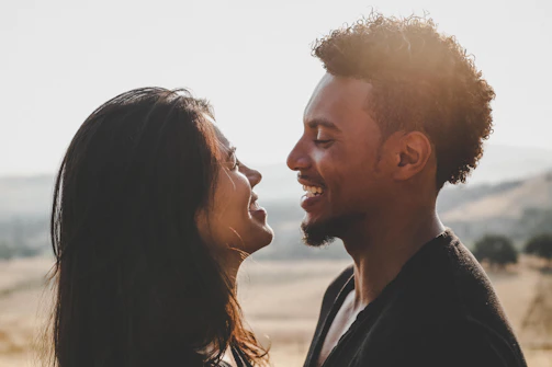 A warm, sunlit portrait session showing a photographer interacting naturally with a happy couple outdoors.