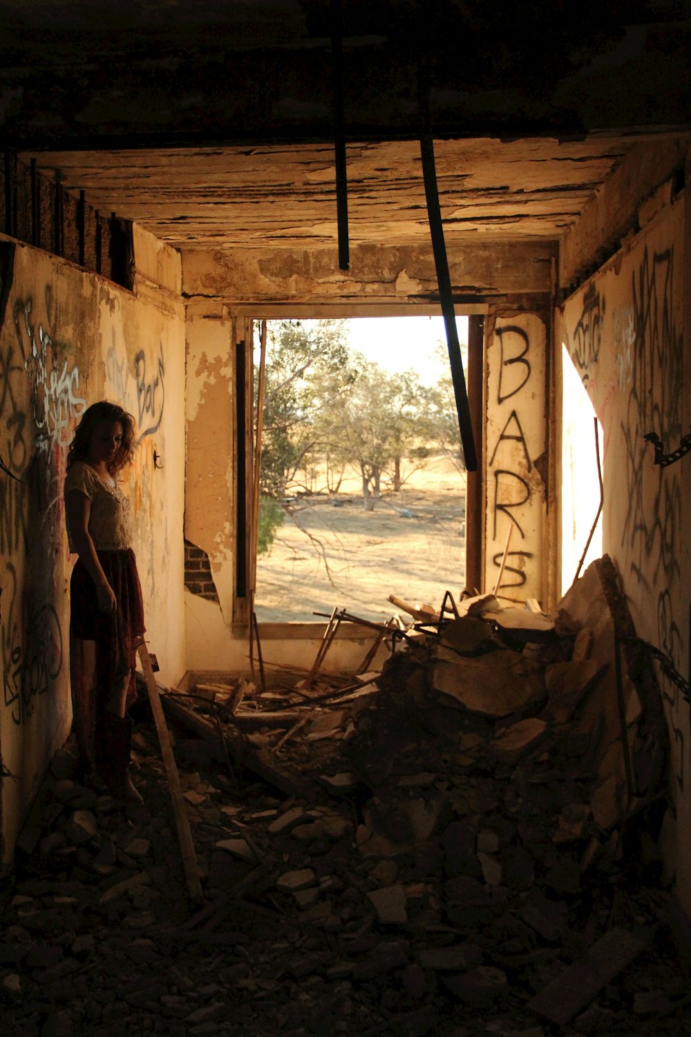 woman standing near wall inside destructed house