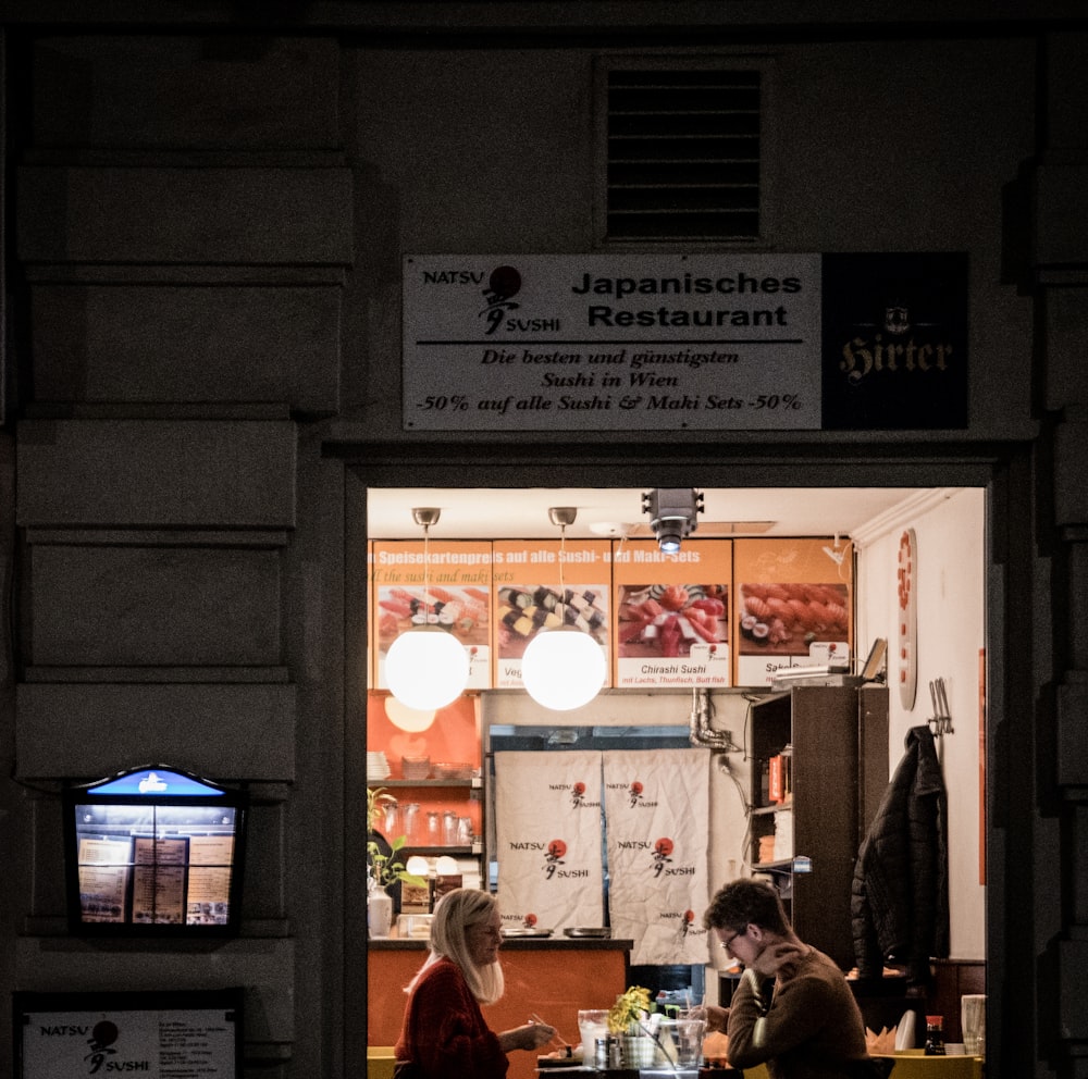 man and woman sitting near dining table inside building during night time