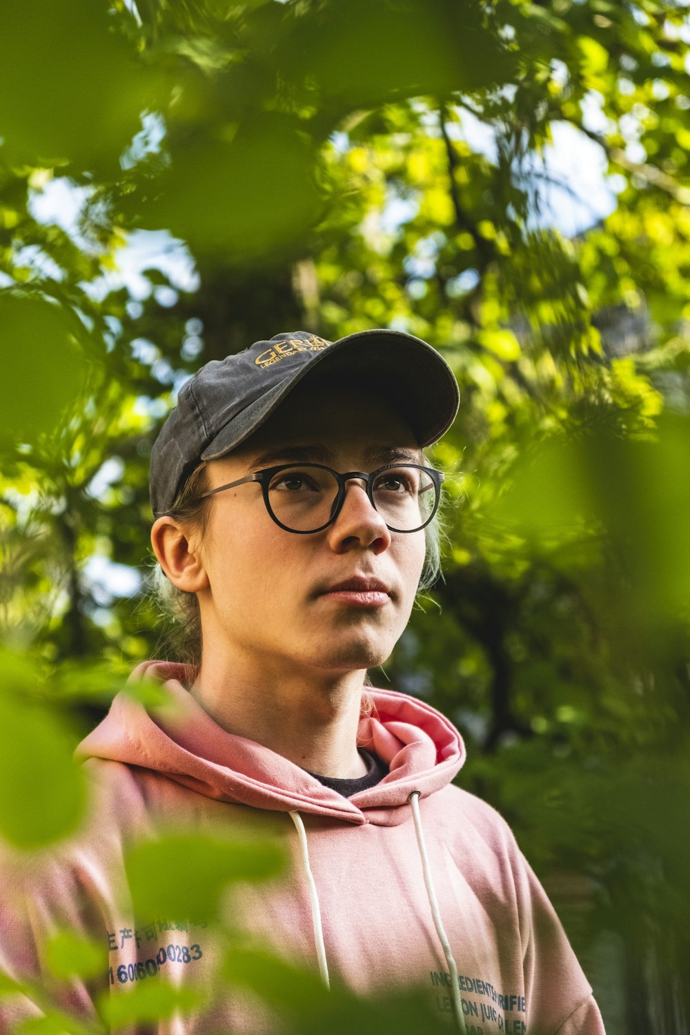 man wearing pullover hoodie and cup standing beside plants