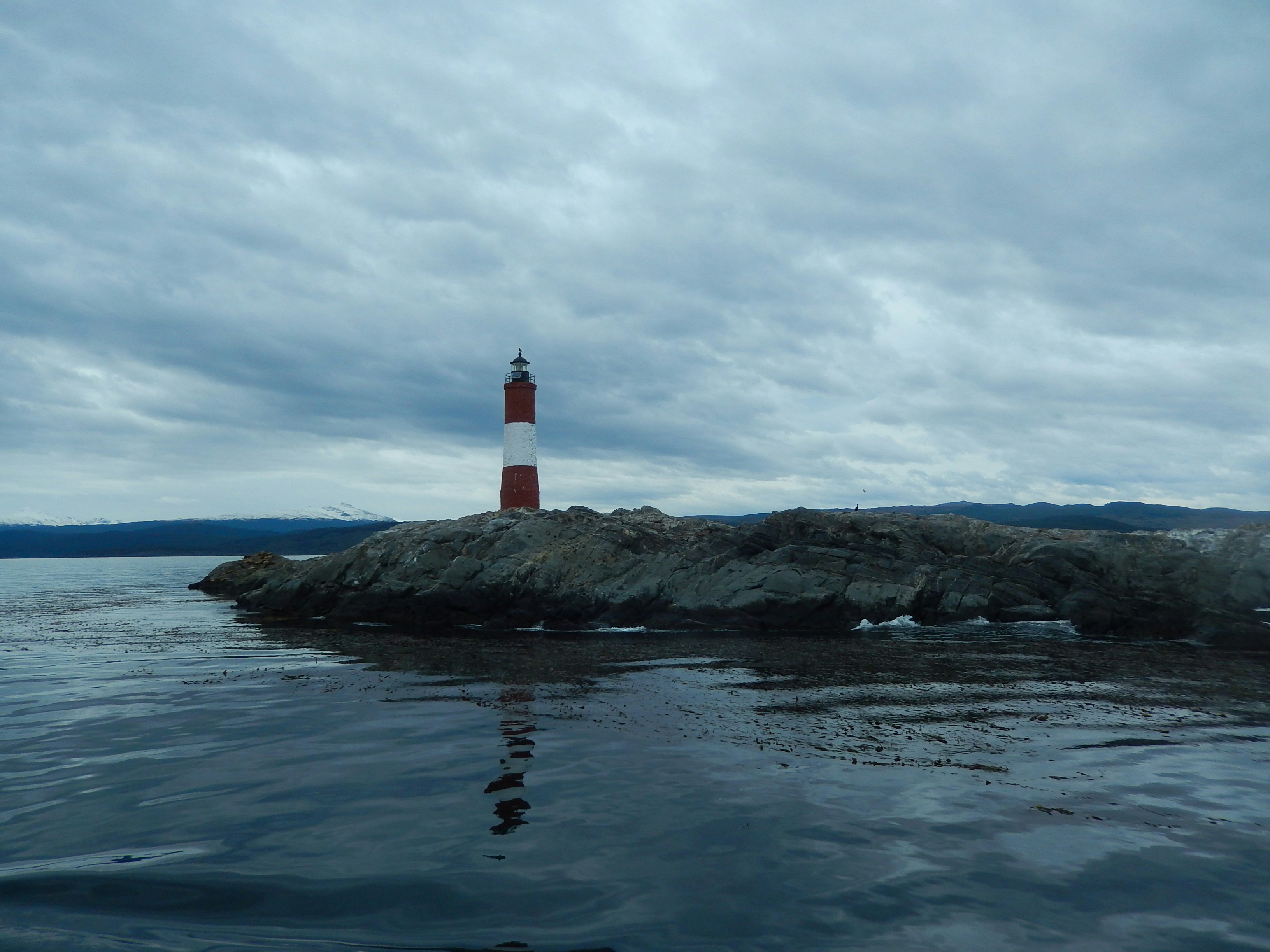 red and white lighthouse on rock islet