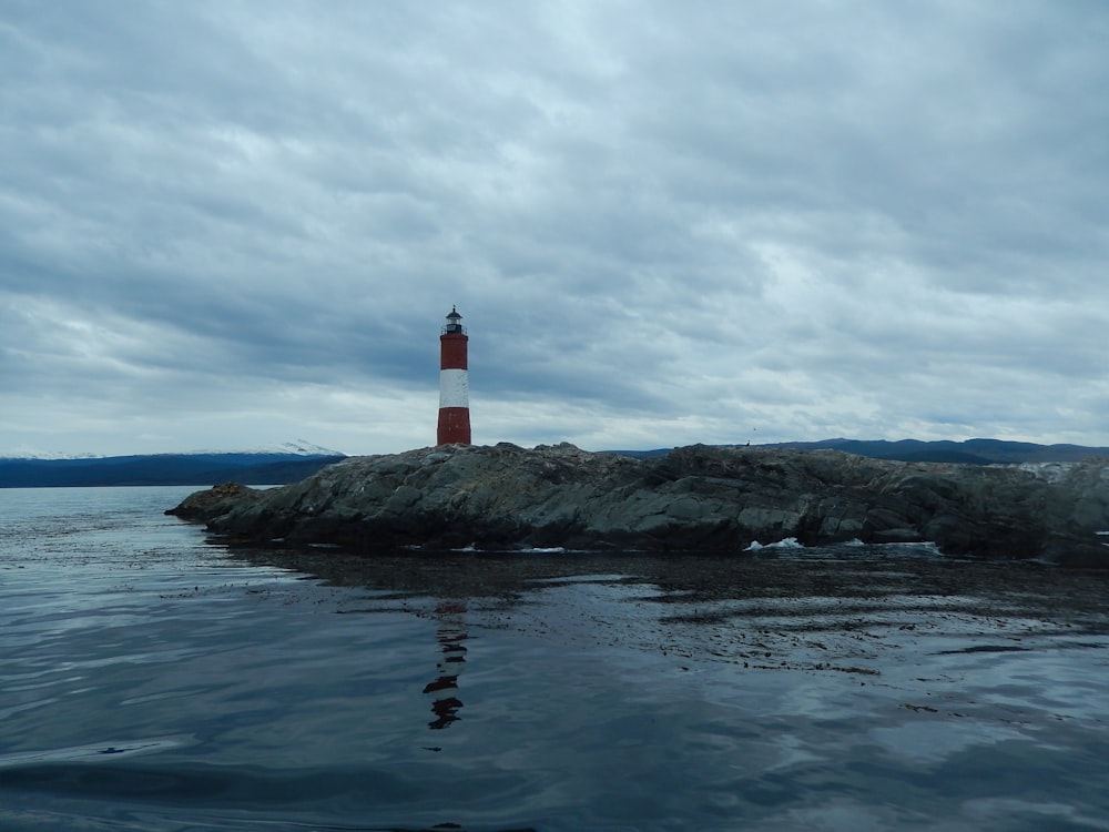 red and white lighthouse on rock islet