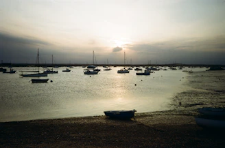 A serene coastal village at sunset with fishing boats anchored near shore.
