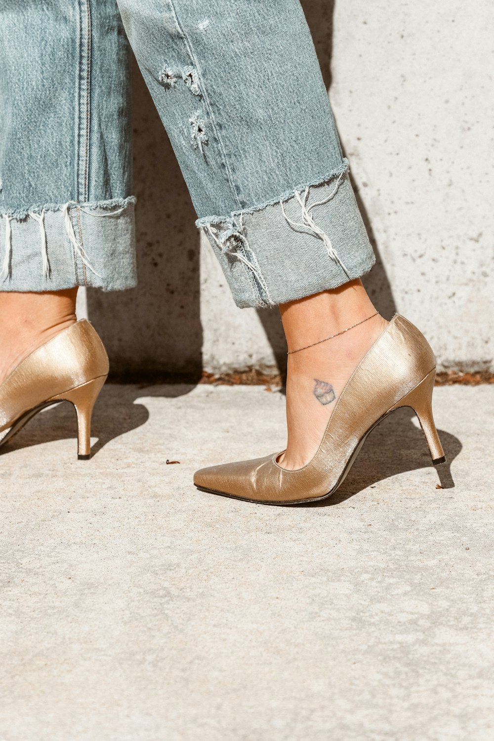 Frau in goldenem Absatzschuh mit blauer Denim-Jeans