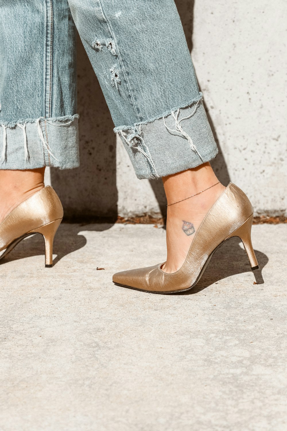 woman in gold heeled shoe with blue denim jeans