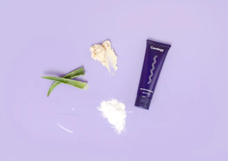 A flat lay of purple-themed skincare products alongside a smartphone showing social media icons.