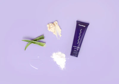 A sleek, minimalistic flat lay of Dermaluxe's tone corrector body moisturizer surrounded by fresh botanical ingredients.