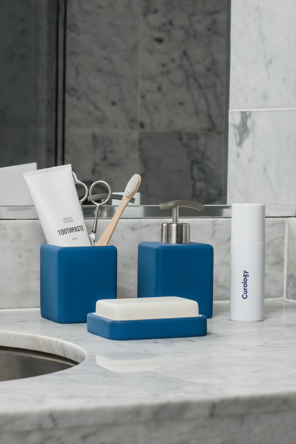 white soft-tube and brown brush in blue container beside pump bottle