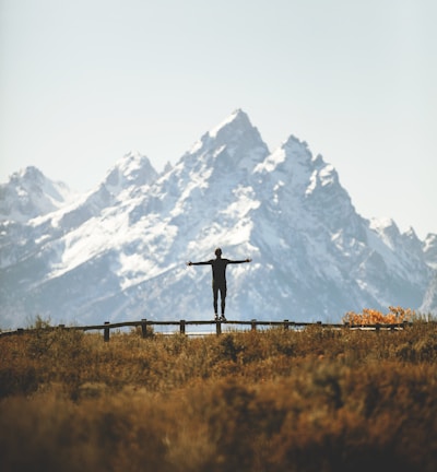 man standing on fence overlooking mountain range