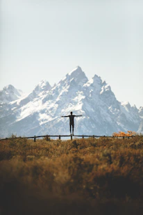man standing on fence overlooking mountain range