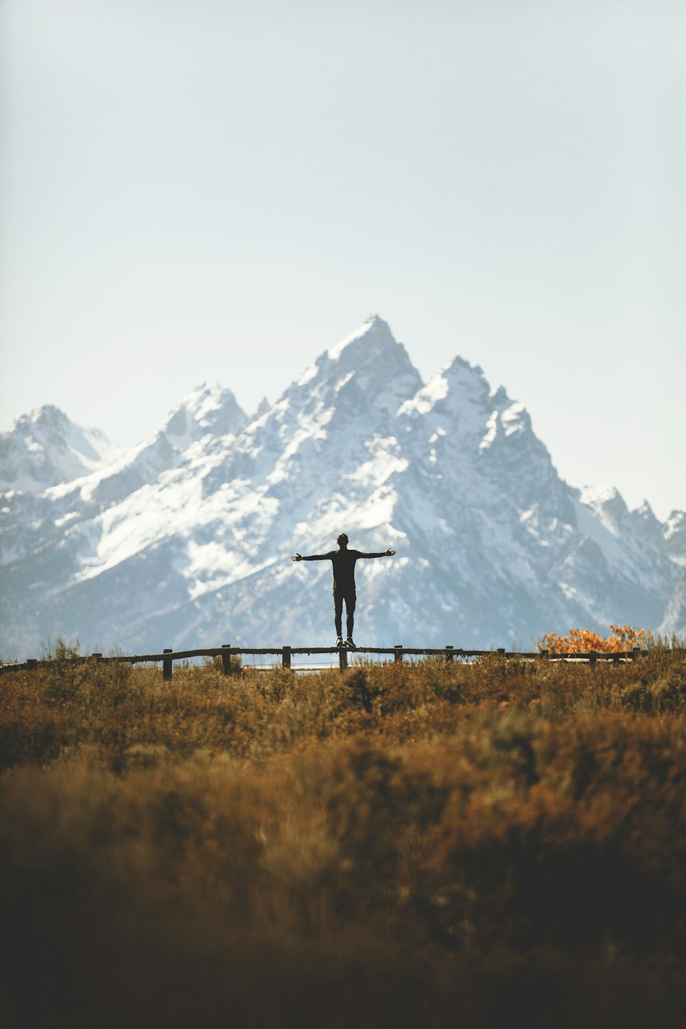 man standing on fence overlooking mountain range