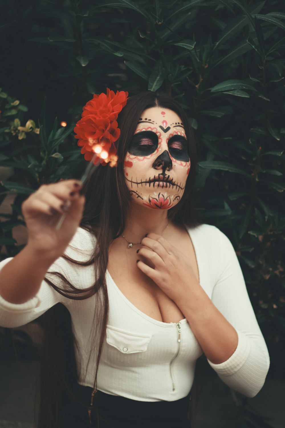 mujer sosteniendo flor con pintura facial