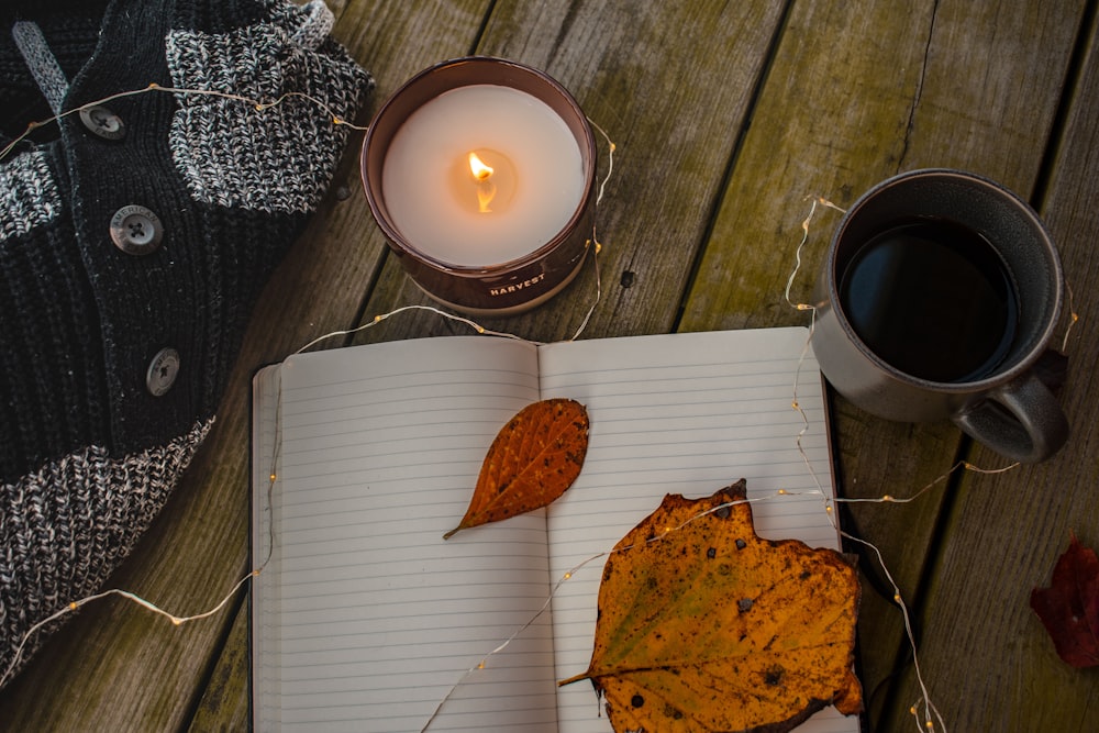 notebook beside mug and candle