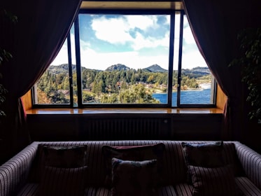 A spacious living room with floor-to-ceiling windows overlooking a forested valley.
