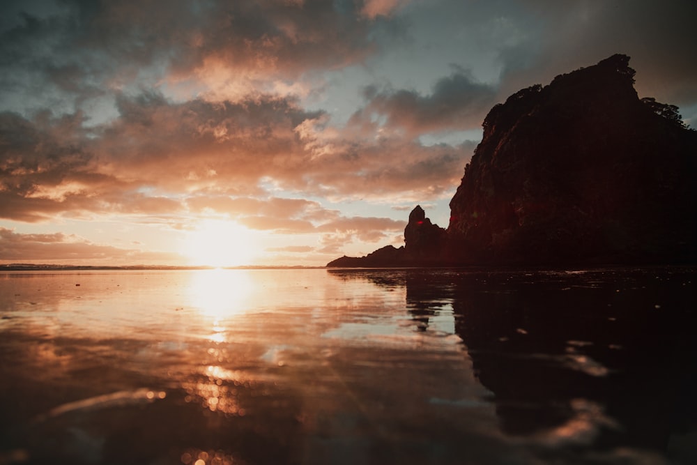 calm body of water near silhouette of mountain