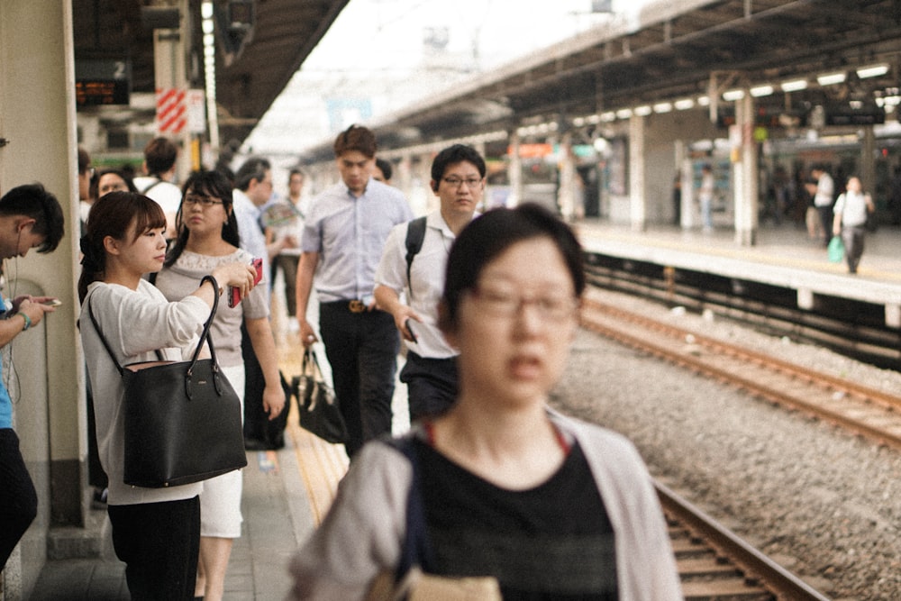 흰 드레스 셔츠와 검은 바지를 입고 기차역을 걷는 남자의 사진