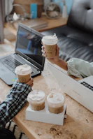 Close-up of hands exchanging ideas over documents and coffee cups.