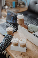 Close-up of hands reviewing business permit paperwork with laptops and coffee cups nearby.