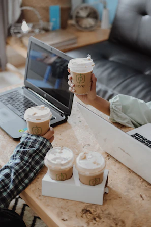 Close-up of hands exchanging ideas over documents and coffee cups.