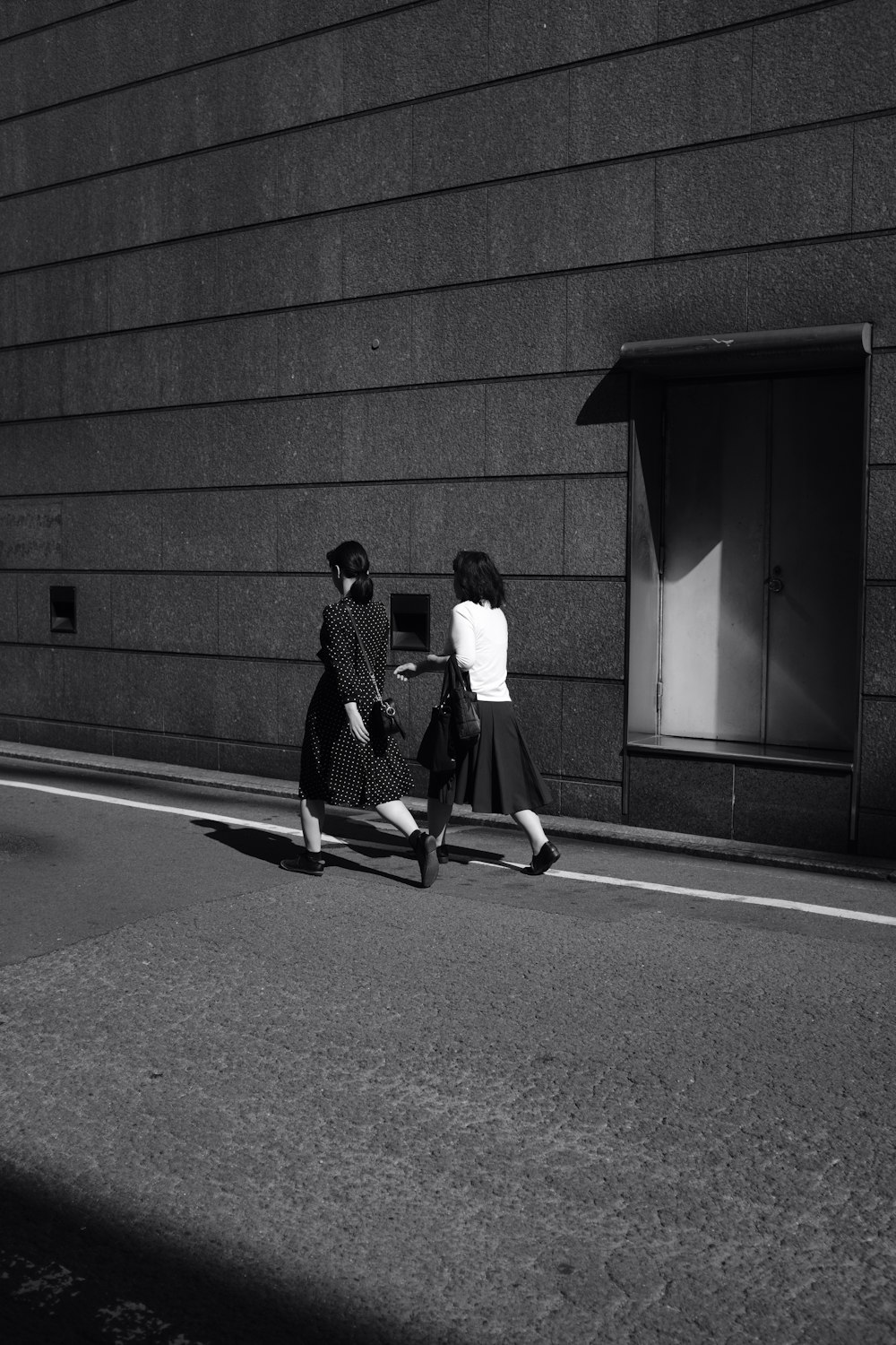 two women walk on the street in monochrome photo