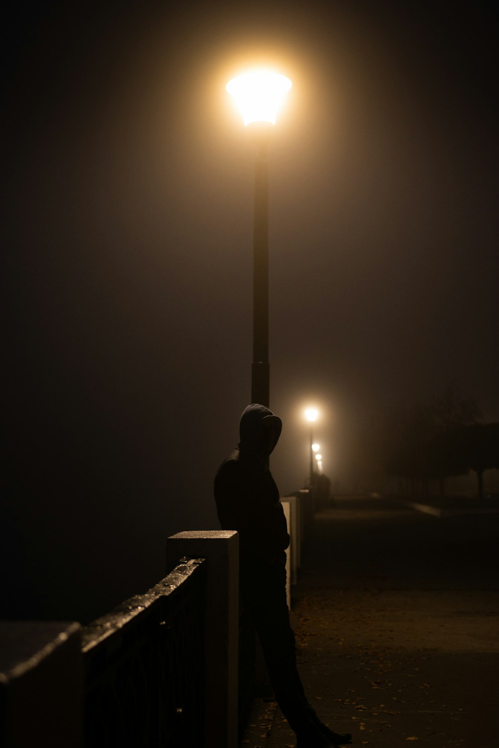 man standing beside fence