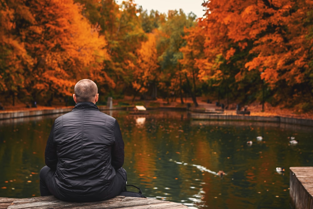 man sitting beside body of water