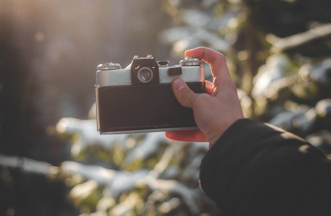 Close-up of a smiling woman holding a vintage camera in natural light