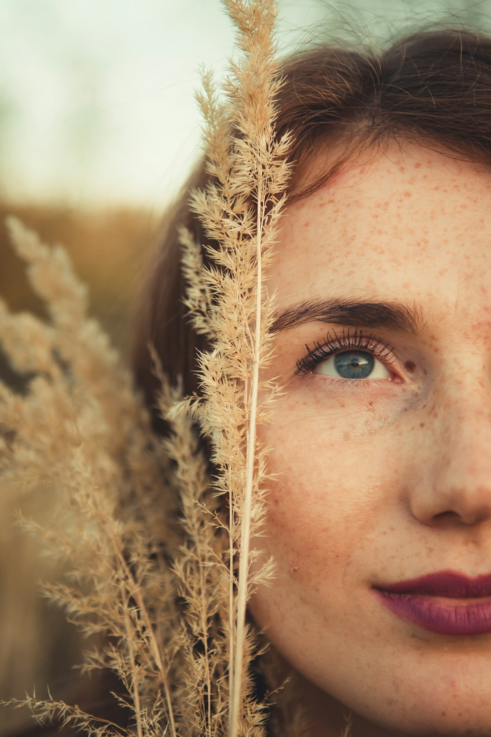 erba marrone accanto al viso della donna