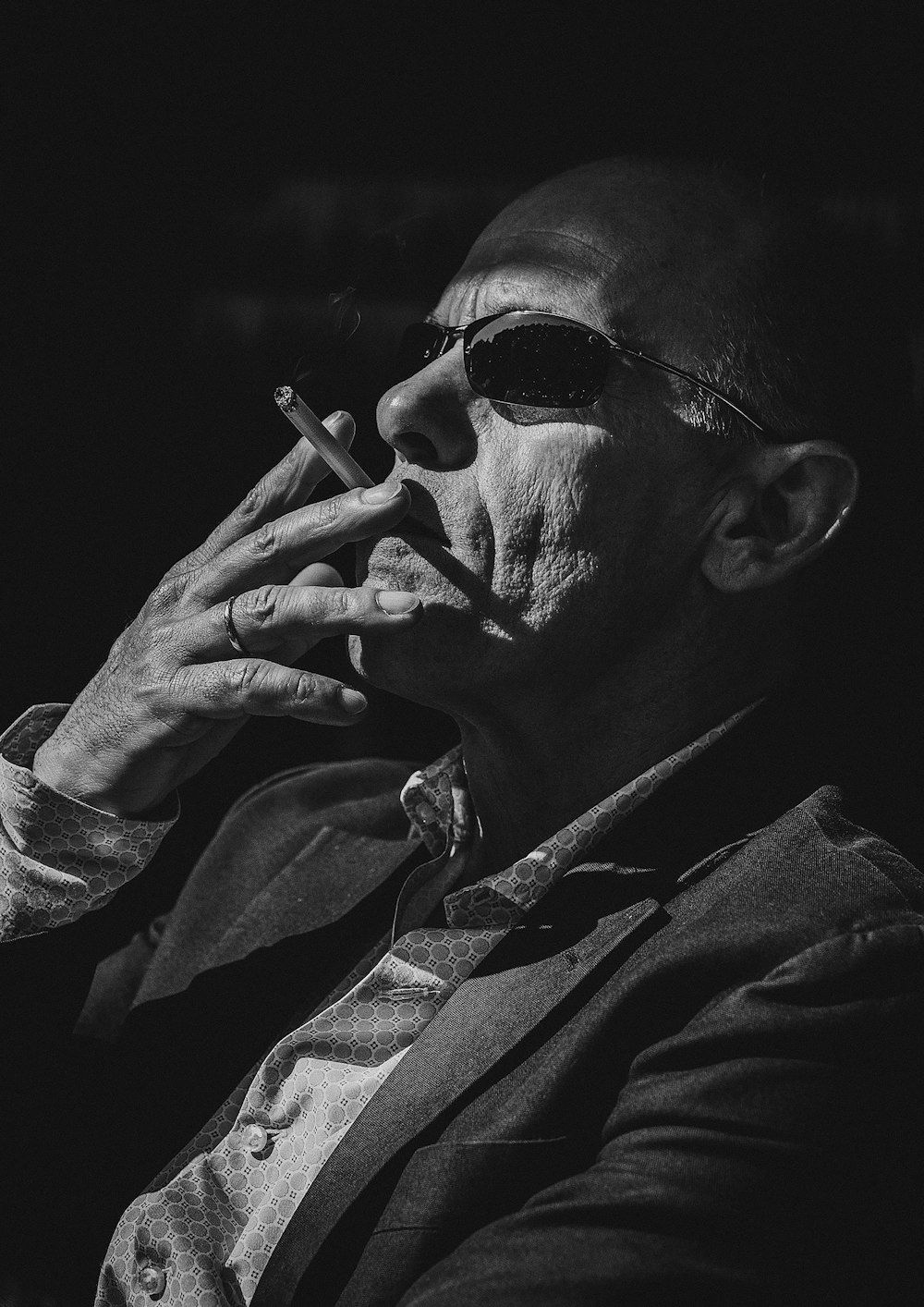 Homem fuma cigarro em foto monocromática