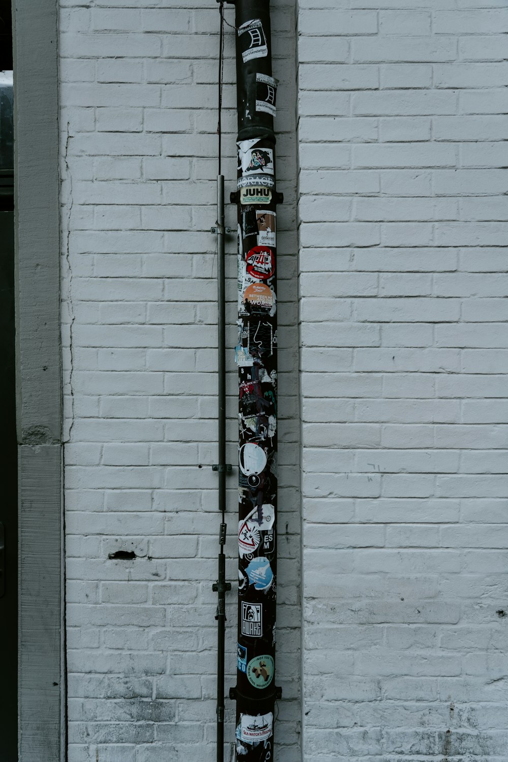pipe with stickers near brick wall