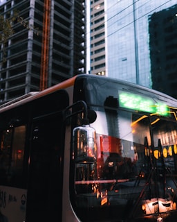 A sleek NYC Sprinters bus parked in front of the iconic Times Square at dusk, city lights glowing.