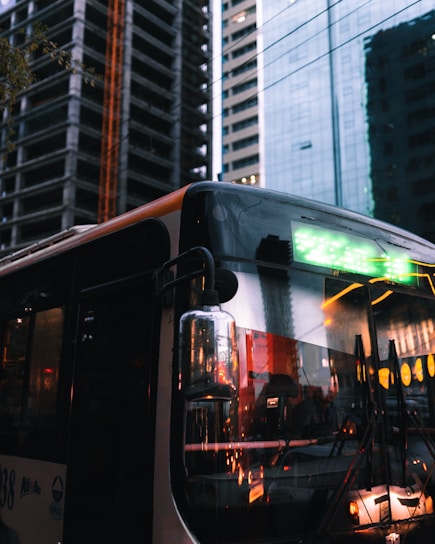 A sleek NYC Sprinters bus parked in front of the iconic Times Square at dusk, city lights glowing.