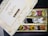 An open box of assorted traditional Indian sweets, known as mithai, with a variety of bright and colorful pieces arranged neatly in compartments. The box displays elegant gold floral designs and inscriptions, with the label 'Dryfruit Sweets Premium 24 Carats Mithai Magic' on the lid.
