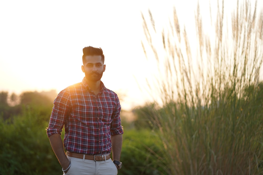 standing man wearing plaid shirt with both hands on pants' pockets