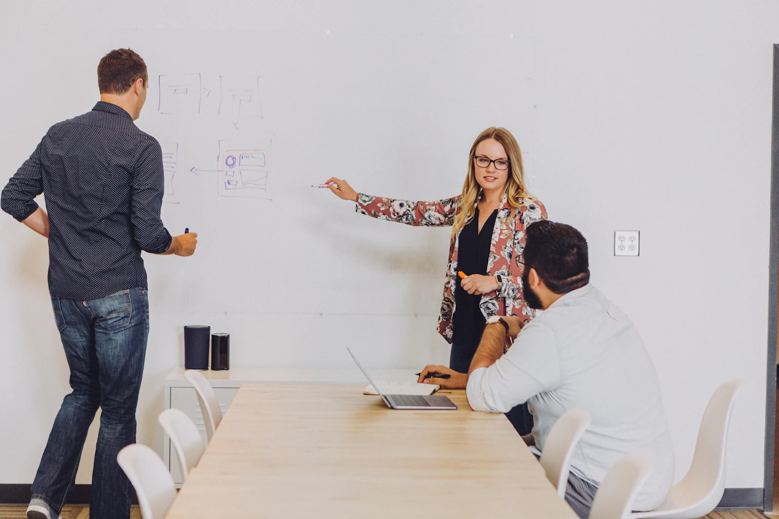 A woman points at a whiteboard during a discussion