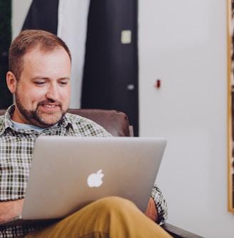 man smiling and using MacBook