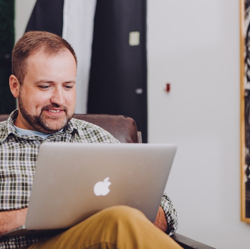 man smiling and using MacBook