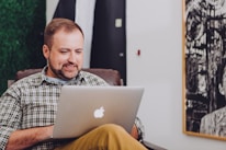 man smiling and using MacBook