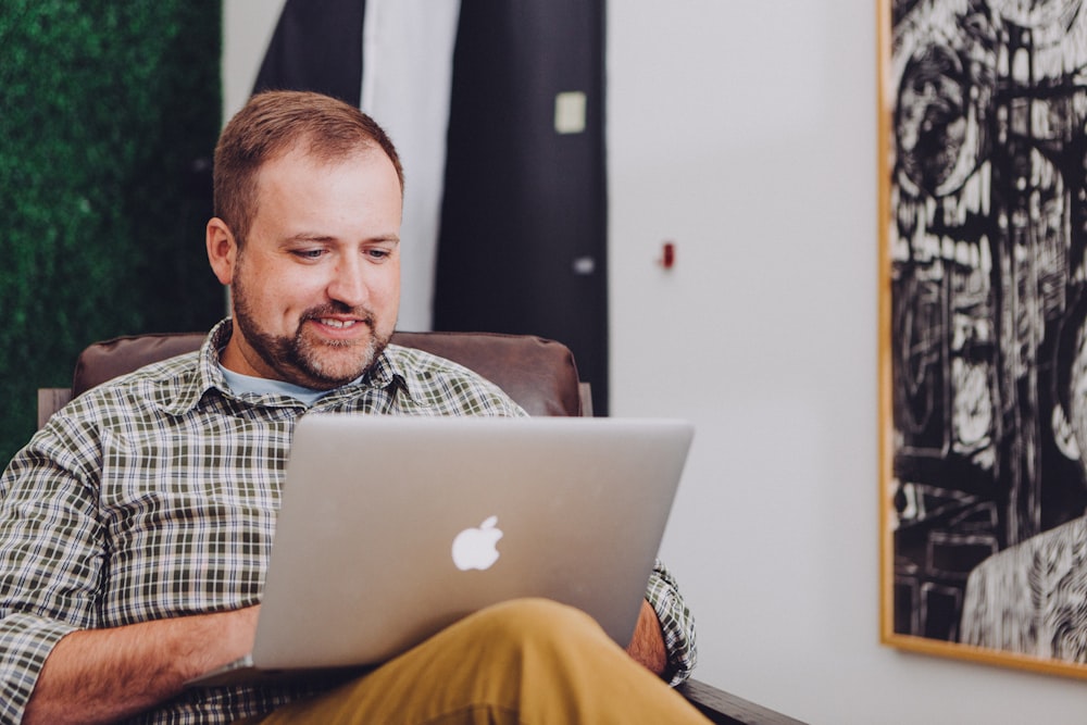 Mann lächelt und benutzt MacBook