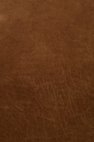 A close-up view of a textured, brown leather surface with visible grain and natural patterns.