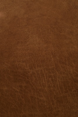 A close-up view of a textured, brown leather surface with visible grain and natural patterns.