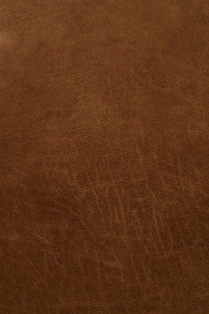 A close-up of warm brown leather grain, standing in for the birch-tar leather of N°VI Cuir Rouge